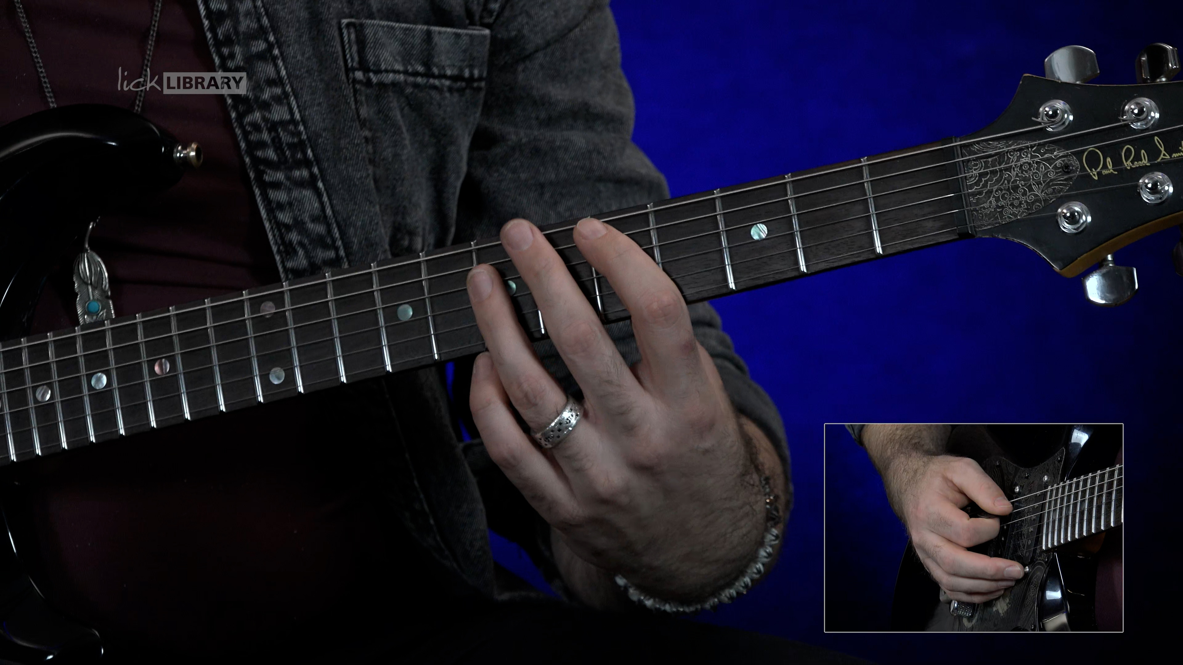 A screenshot of a close-up of a guitar instructor explaining a fretboard.